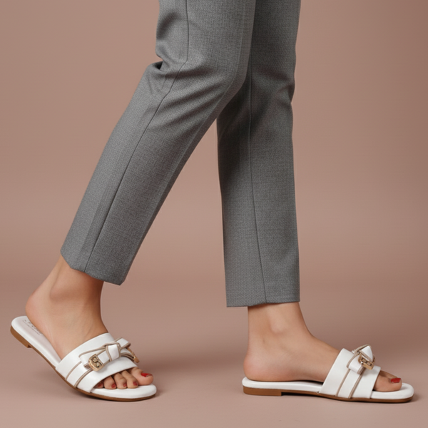 White sandals worn with gray pants on a beige background