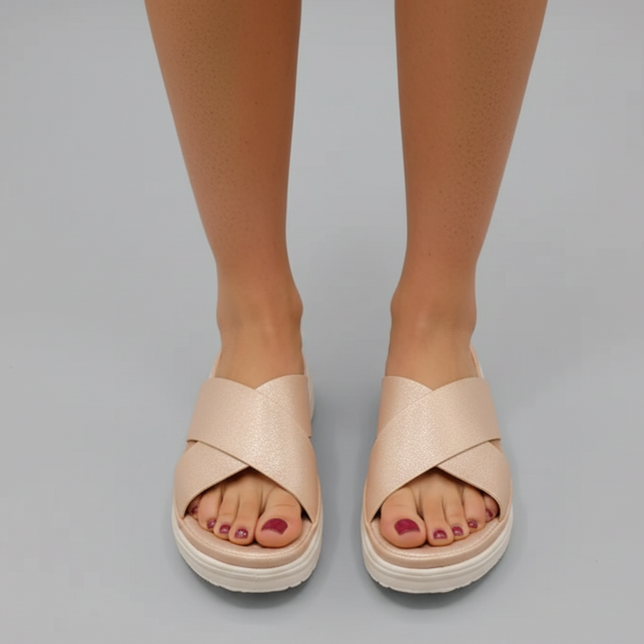 Beige sandals worn by a person on a gray background