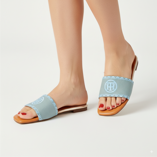 Light blue sandals with a brand logo worn by a person on a white background