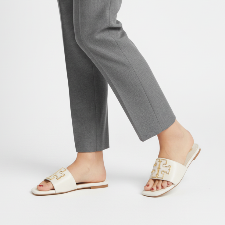 Person wearing gray pants and white sandals on a light gray background