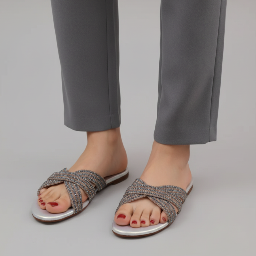 Person wearing silver sandals with交叉straps on a plain background