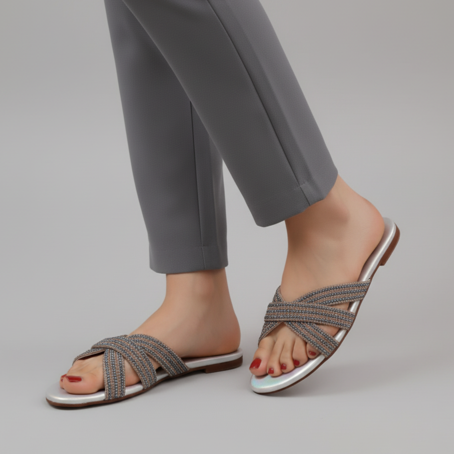 Gray sandals worn with gray pants on a plain background