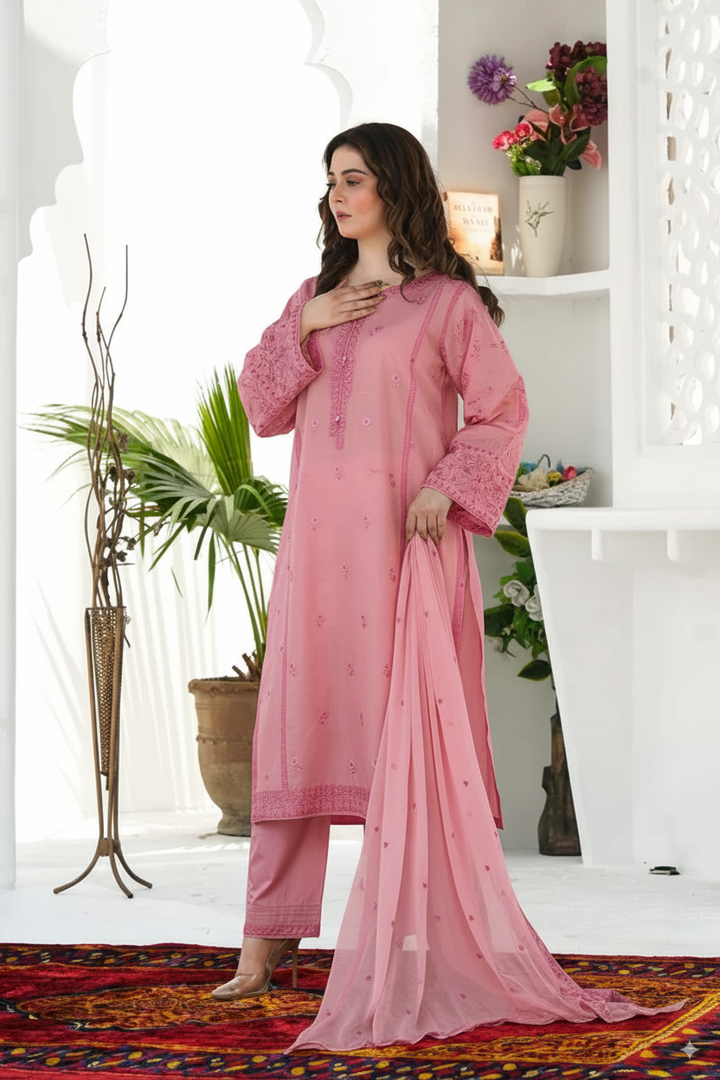 Woman in a pink traditional outfit standing in a bright room with plants and decor.