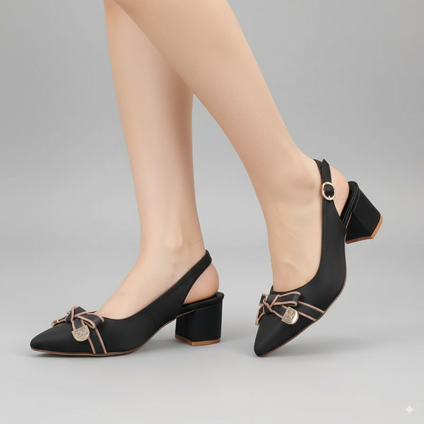 Black high-heeled shoes with decorative bows worn by a person on a gray background