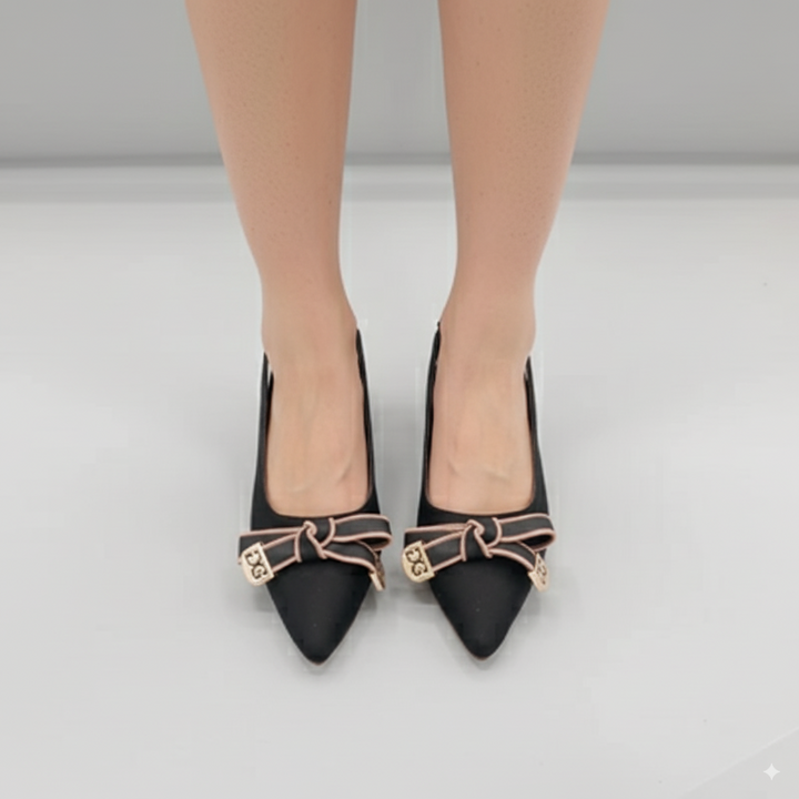 Black high-heeled shoes with decorative bows on a neutral background