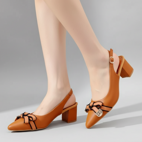 Brown high-heeled shoes with bow details worn by a person on a gray background