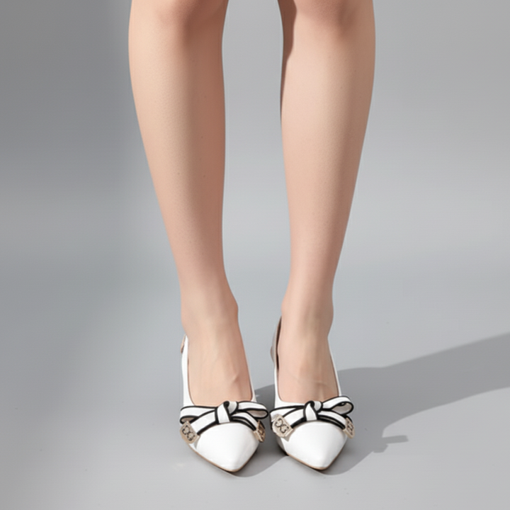 White high-heeled shoes with decorative bows on a gray background