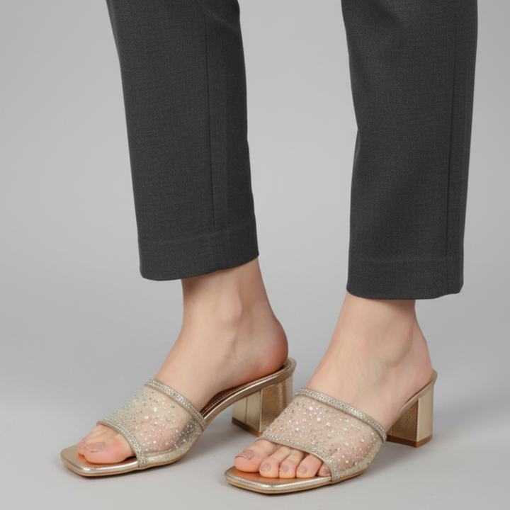 Beige sandals worn with black pants on a gray background