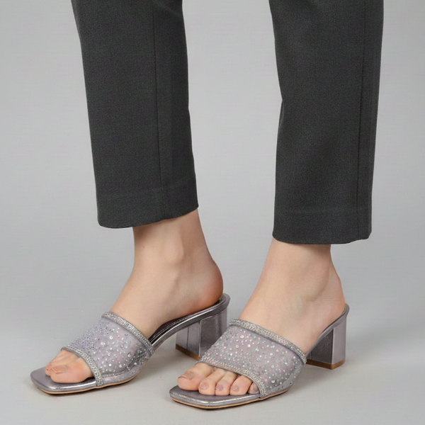 Gray sandals worn with black pants on a gray background