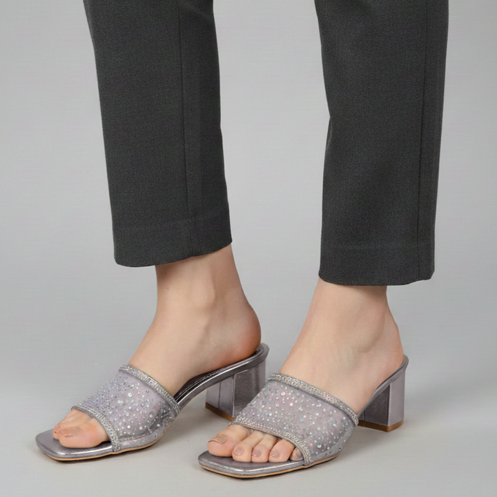 Gray sandals worn with black pants on a gray background