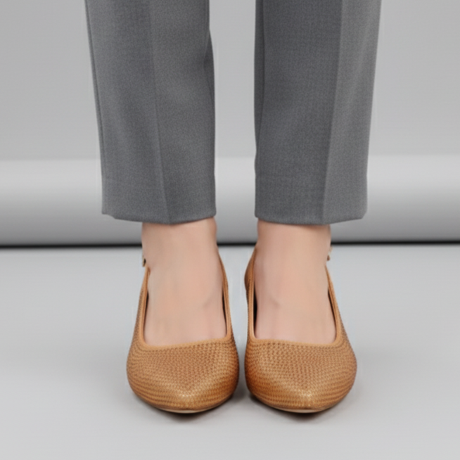 Person wearing brown shoes and gray pants on a plain background