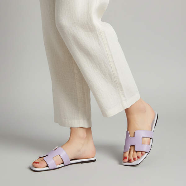 Person wearing light purple sandals on a plain background