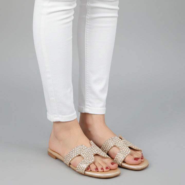 Pearl sandals worn with white jeans on a gray background