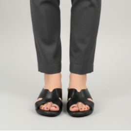 Person wearing black pants and sandals on a plain background