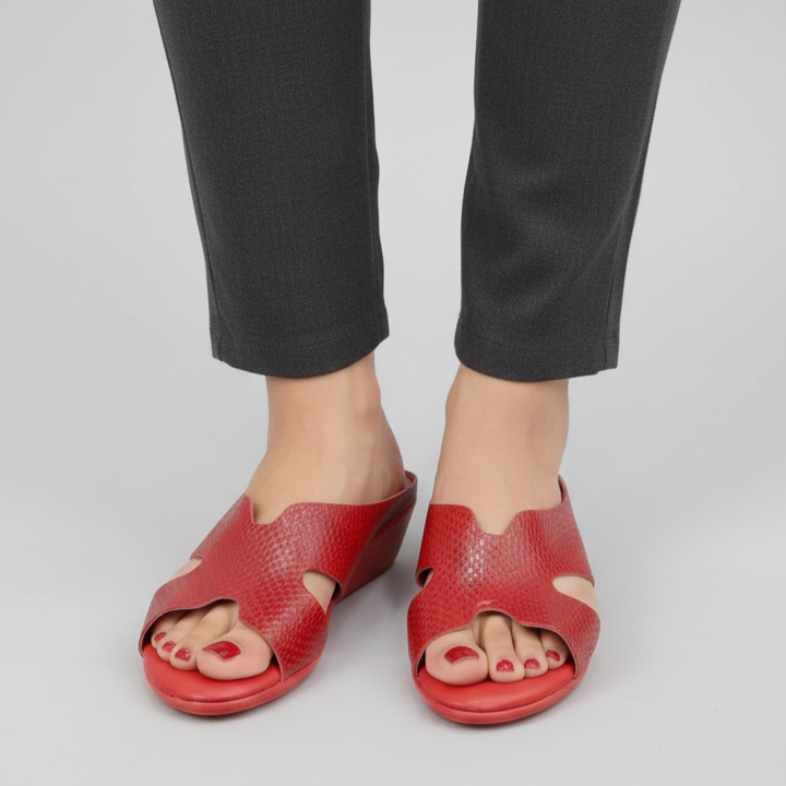 Red sandals worn with black pants on a light gray background
