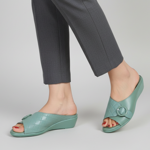 Teal open-toe shoes worn with gray pants on a light gray background