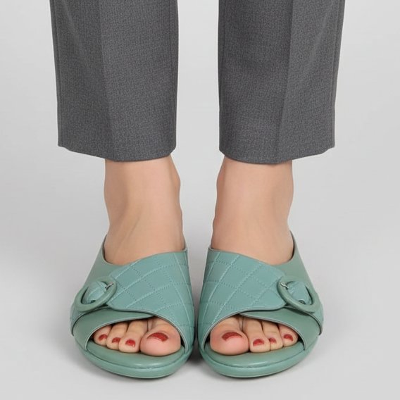 Teal open-toe shoes worn with gray pants on a light gray background