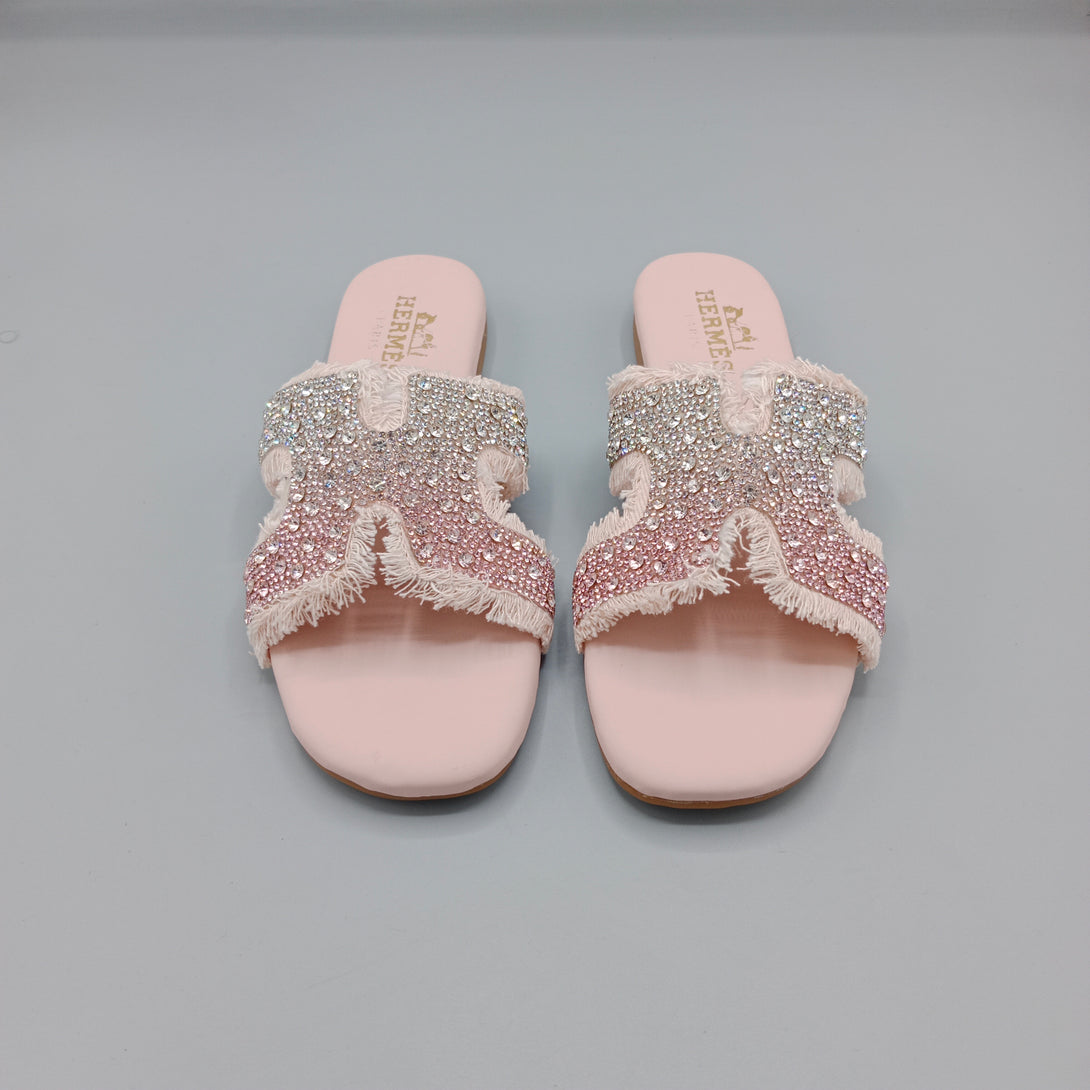 Pair of pink sandals with embellished straps on a gray background