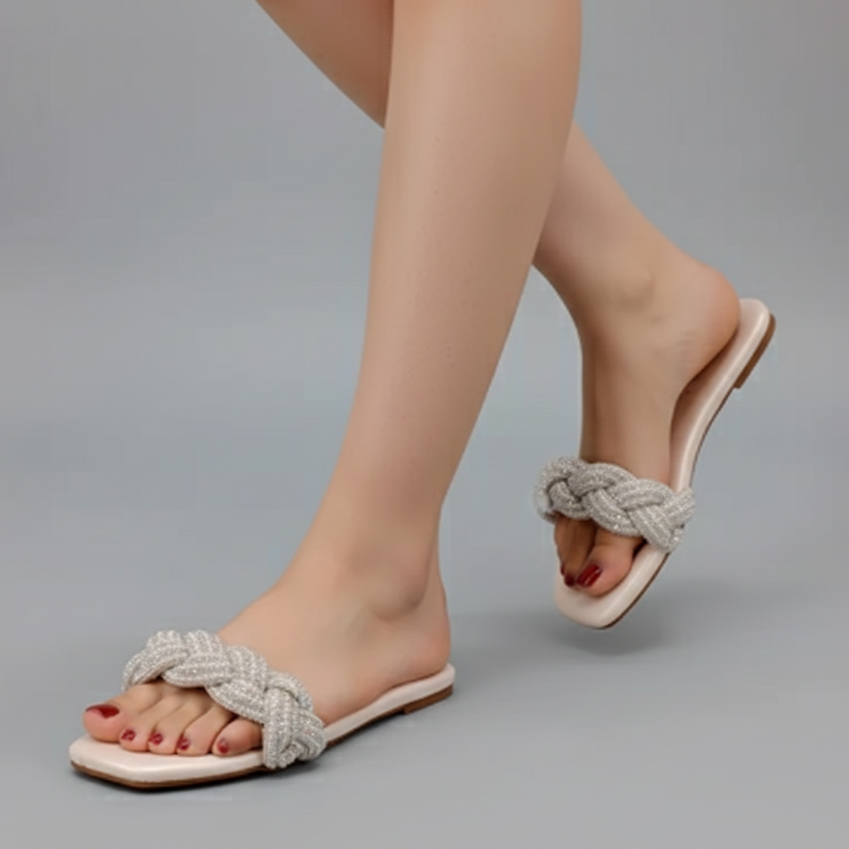 White sandals with rope detailing worn by a person on a gray background