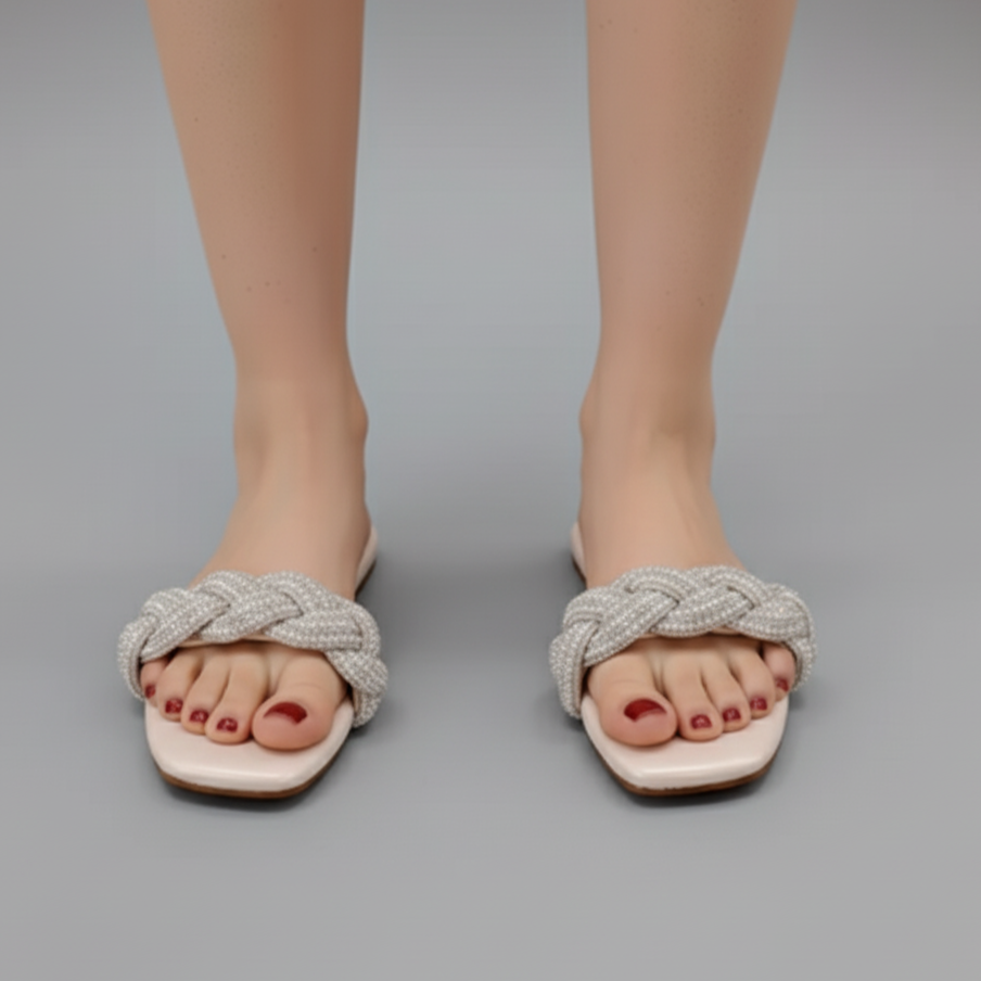 White sandals with braided straps worn by a person on a gray background